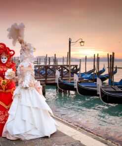 Due maschere in stile settecentesco passeggiano a Venezia guardando le gondole durante il Carnevale